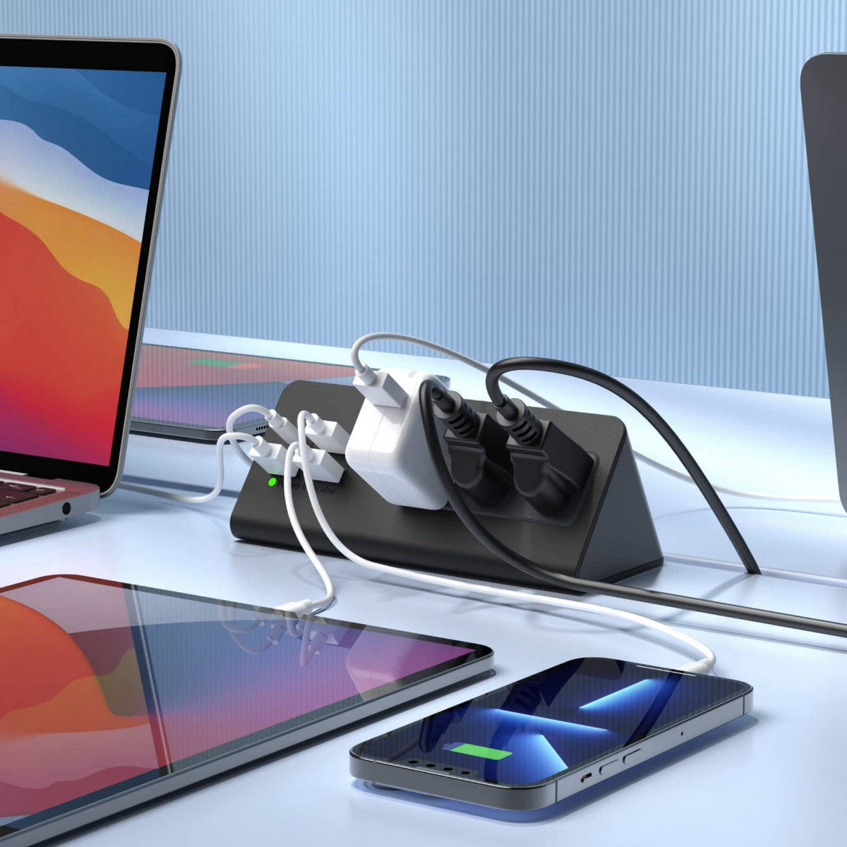 Multiple electronic devices connected to a power strip on a desk.